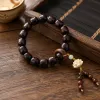 A dark brown wooden lotus-carved bracelet with small beaded tassels details Picture